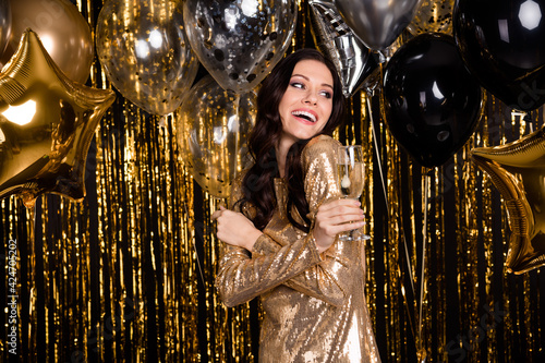 Photo of optimistic brunette curly hairdo lady with balloons glass look empty space wear nice dress isolated on gold color background