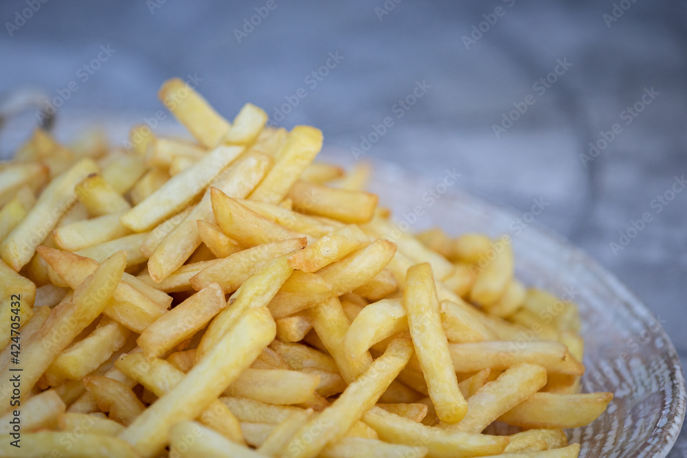 Large plate of fries. A plate of potatoes is on the table. Quick snack and junk food concept Large plate of fries. A plate of potatoes is on the table. Quick snack and junk food concept