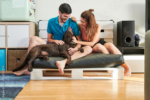 young couple enjoying a tender moment at home with their chocolate labrador dog