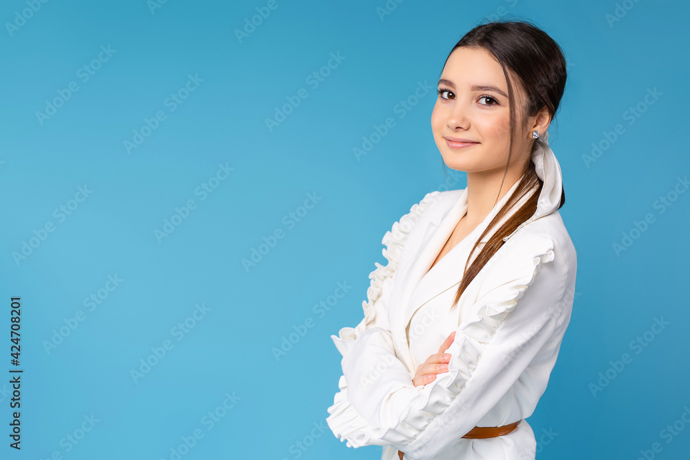 Studio photo of a young businesswoman posing on a blue background in a white office suit. Empty side advertising space. Studio photo of a young businesswoman posing on a blue background in a white office suit. Empty side advertising space.