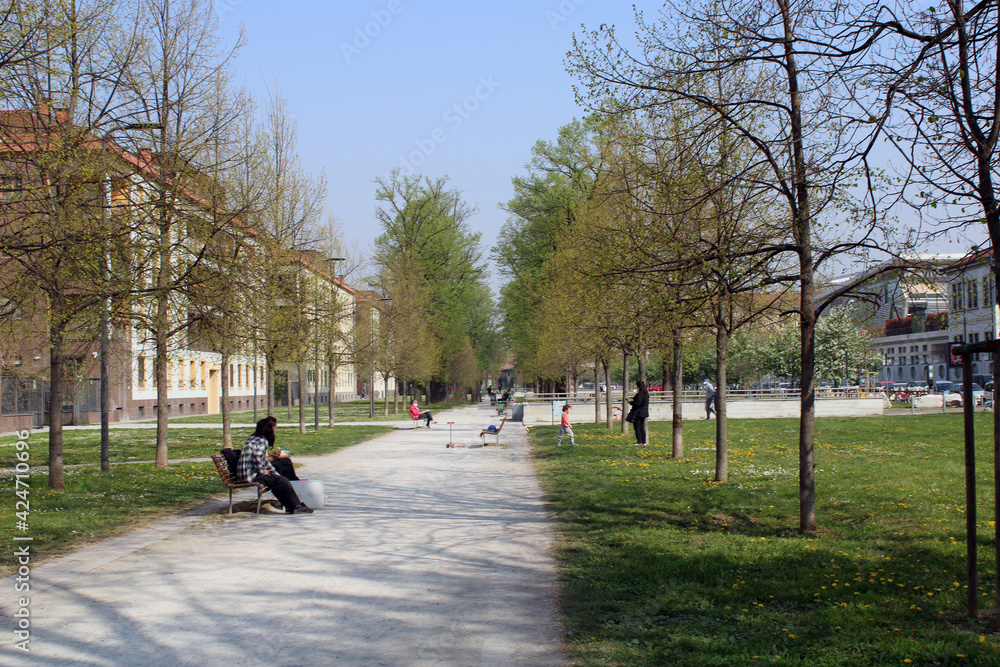 Naklejka premium Parco di Miilano con alberi panchine e persone con mascherina anti Covid