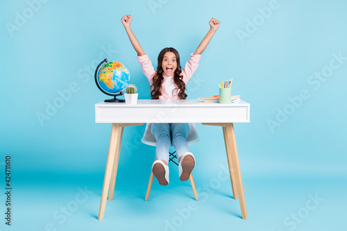 Full size photo of young happy excited cheerful good mood girl raise fists end of lesson isolated on blue color background photo