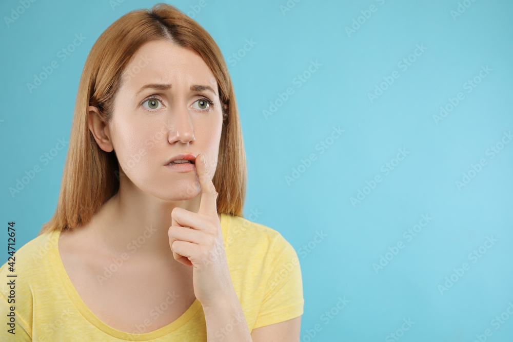 Upset woman suffering from herpes on light blue background. Space for text Upset woman suffering from herpes on light blue background. Space for text