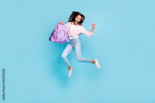 Full size photo of young happe excited crazy good mood schoolgirl jump passed exams isolated on blue color background