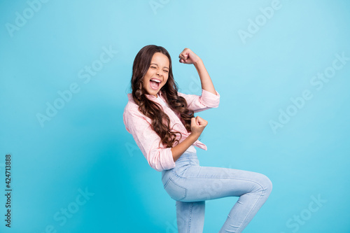 Photo of young happy excited cheerful good mood girl raise fists in victory with open mouth isolated on blue color background