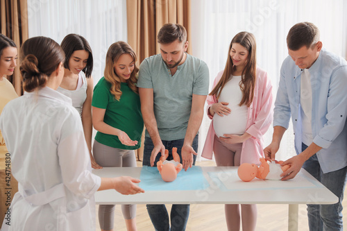Foto Future fathers and pregnant women learning how to swaddle baby at courses for ex