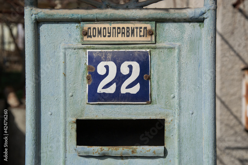 Old house’s metal aged door with mailbox and sign 22 number, and text “house manager”, urban concept, green door