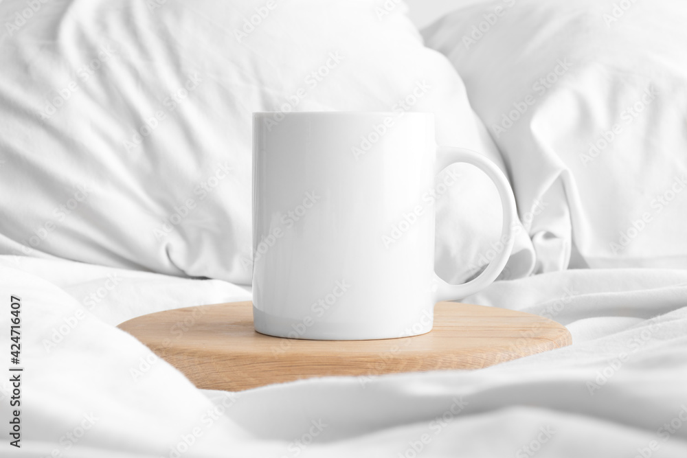 White mug mockup on the bed.