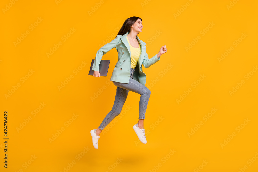 Full length photo of shiny pretty lady dressed turquoise jacket jumping running holding gadget isolated yellow color background