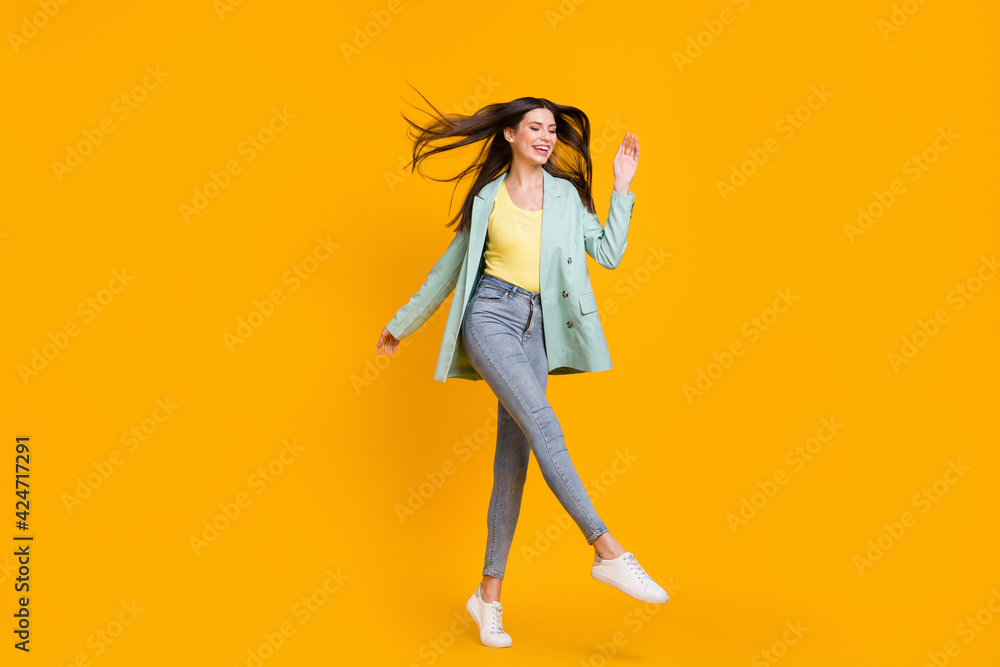 Full size photo of young cheerful smiling positive lovely girl dancing with flying hair isolated on yellow color background Full size photo of young cheerful smiling positive lovely girl dancing with flying hair isolated on yellow color background