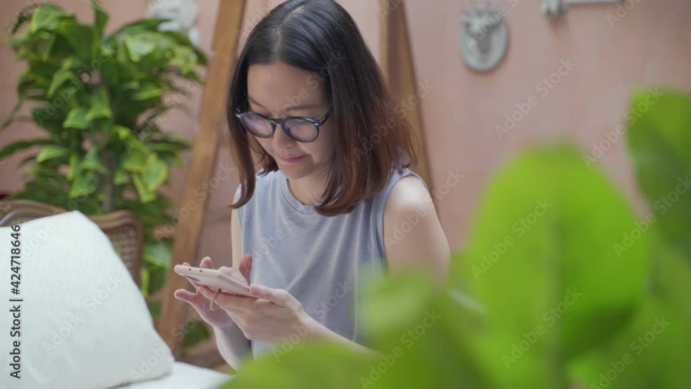 asian woman using application on mobile smartphone on tropical room style. asian woman using application on mobile smartphone on tropical room style.