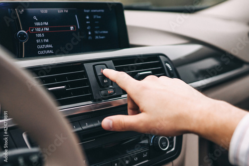 Close up of hand reaching for button in modern car