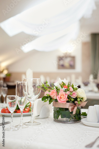 Beautiful setting of wedding party in restaurant. Table decorated with flowers. Elegant cafe decoration © Olga Mishyna