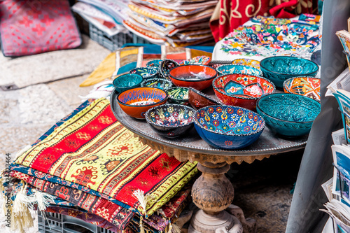 Multicolored handmade bowls and colored rugs and shawls in the arab market (593)
