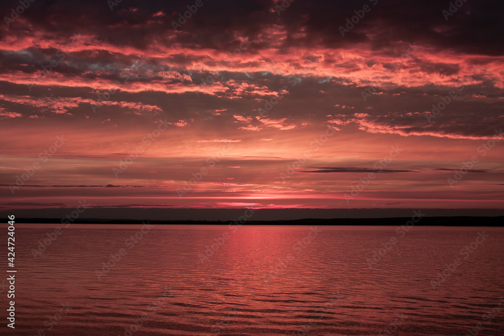 Horizontal moody seascape photography of a pink twilight with cloudy sky over calm sea