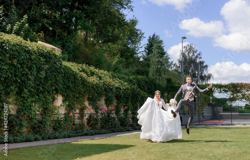 Front view of amazing wedding couple walking on the beautiful hotel yard and having fun. photo