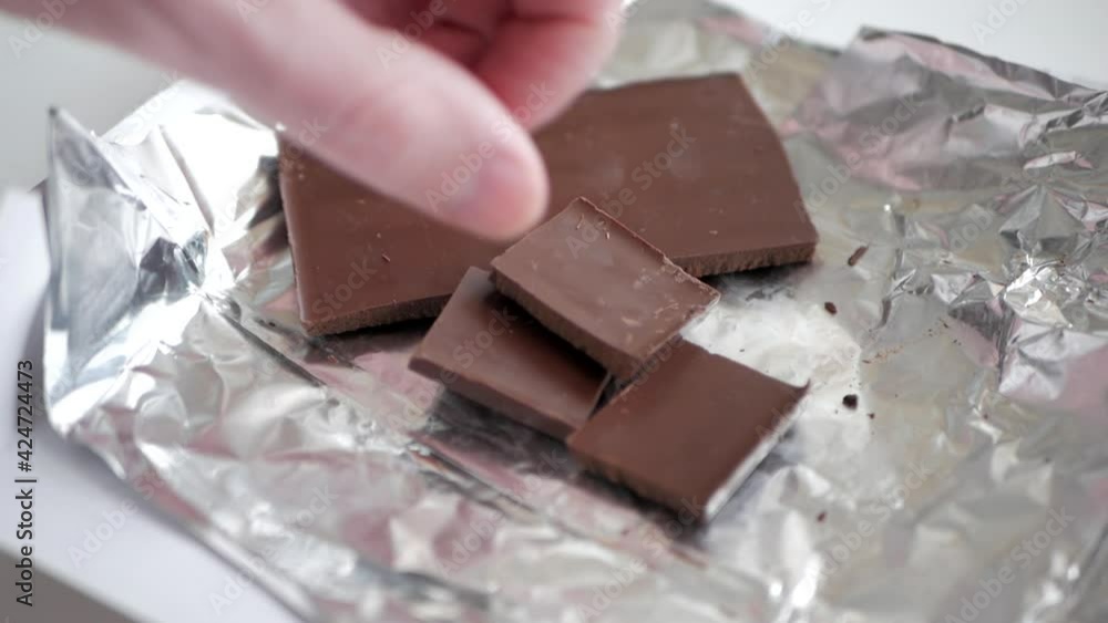 Several chocolate bars are placed next to each other. The man's hand