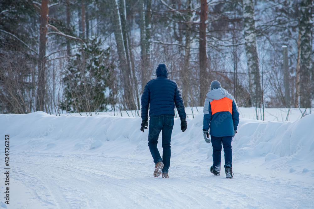 Father and Son Walking in a Winter Forest. Father and son bonding and at the same time exercising through walking in the snow-covered forest.