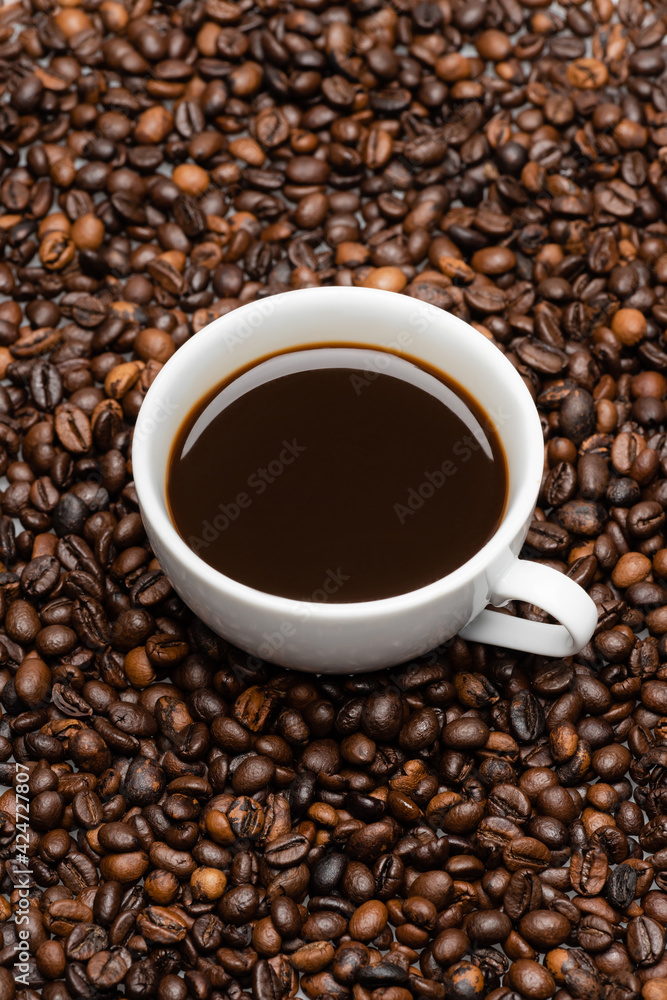 high angle view of white cup with prepared coffee on brown beans high angle view of white cup with prepared coffee on brown beans