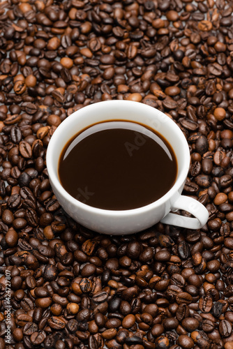 high angle view of white cup with prepared coffee on brown beans