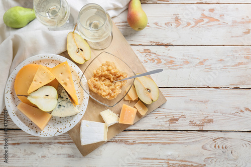 Tasty pear jam with different cheeses and wine on white wooden background