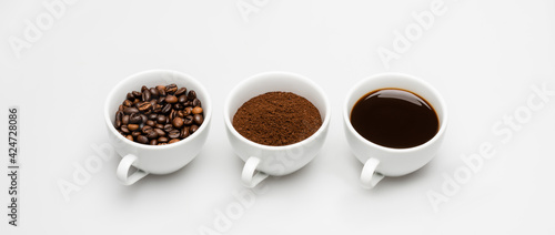 cups with prepared and ground coffee near beans on white, banner