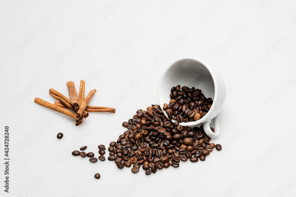 cinnamon sticks near cup with fresh coffee beans on white cinnamon sticks near cup with fresh coffee beans on white