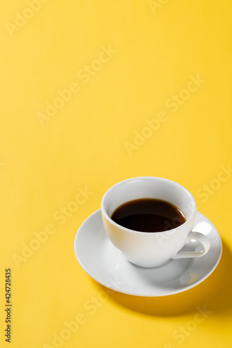 Black coffee in white cup on yellow background