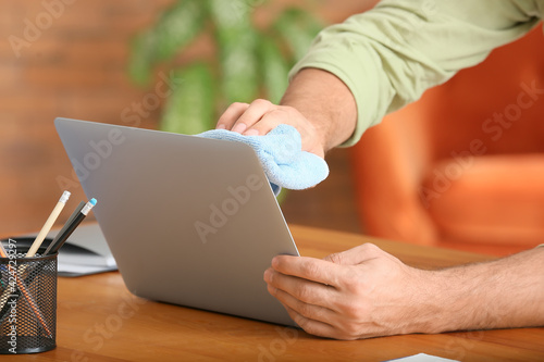 Young man cleaning laptop at home, closeup