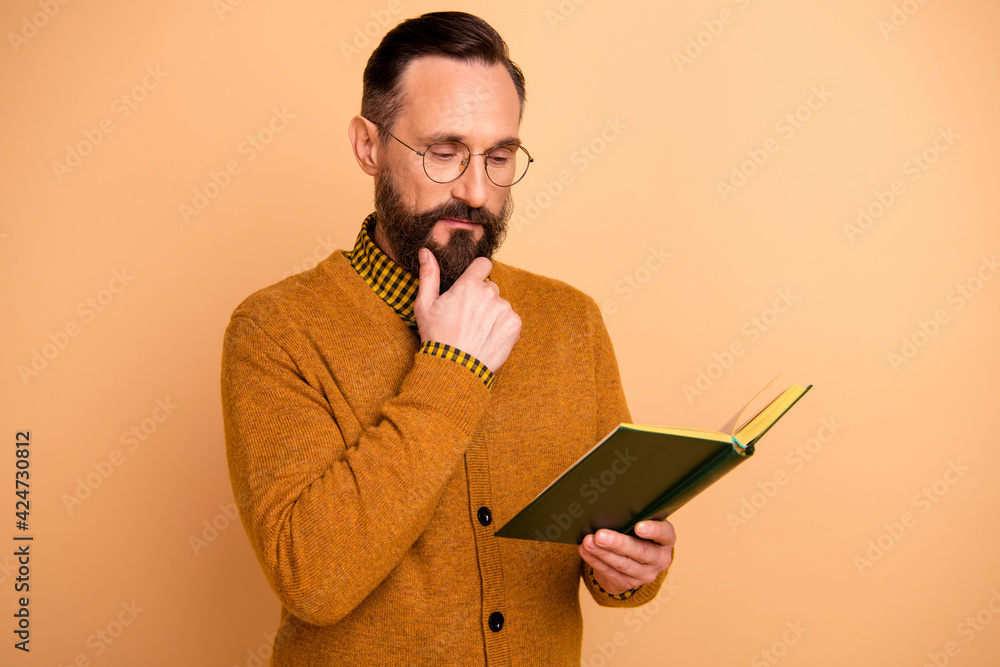 Portrait of nice brunet hairdo serious man read book wear spectacles brown cardigan isolated on beige color background Portrait of nice brunet hairdo serious man read book wear spectacles brown cardigan isolated on beige color background