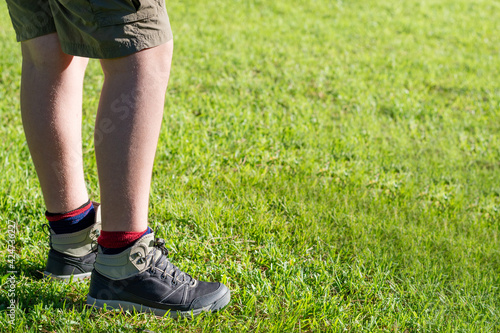 legs of young hiker while walking on the grass.
