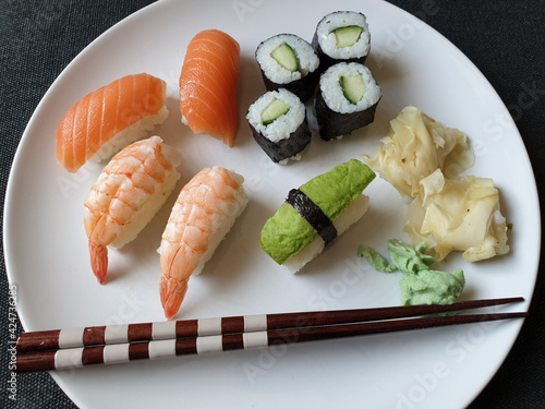 Selection of fish and vegetable sushi on a white plate with ginger and wasabi sauce