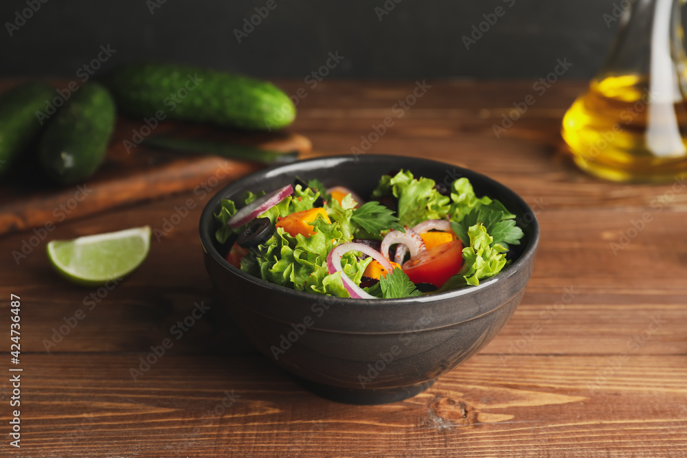 Bowl of fresh salad with vegetables on wooden background