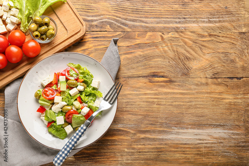 Plate with fresh Greek salad on wooden background
