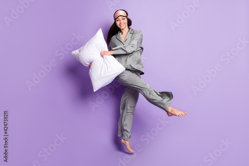 Full length body size photo of pretty woman in grey sleepwear dancing with pillow smiling isolated pastel violet color background