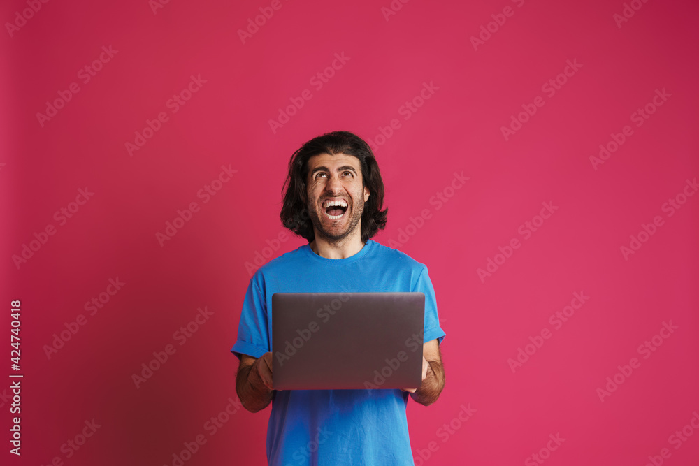 Obraz premium Unshaven excited man screaming and holding laptop