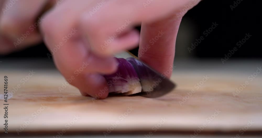 Closeup view of a woman hands cut red onion into slices with a knife. Red onions ring. Preparing food. Cutting the onion. Process of cooking. Closeup view of a woman hands cut red onion into slices with a knife. Red onions ring. Preparing food. Cutting the onion. Process of cooking.