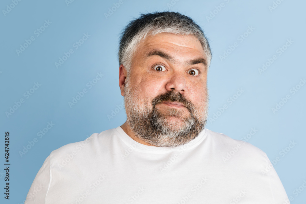Handsome caucasian plus size male model isolated on blue studio background. Concept of inclusion, human emotions, facial expression Handsome caucasian plus size male model isolated on blue studio background. Concept of inclusion, human emotions, facial expression