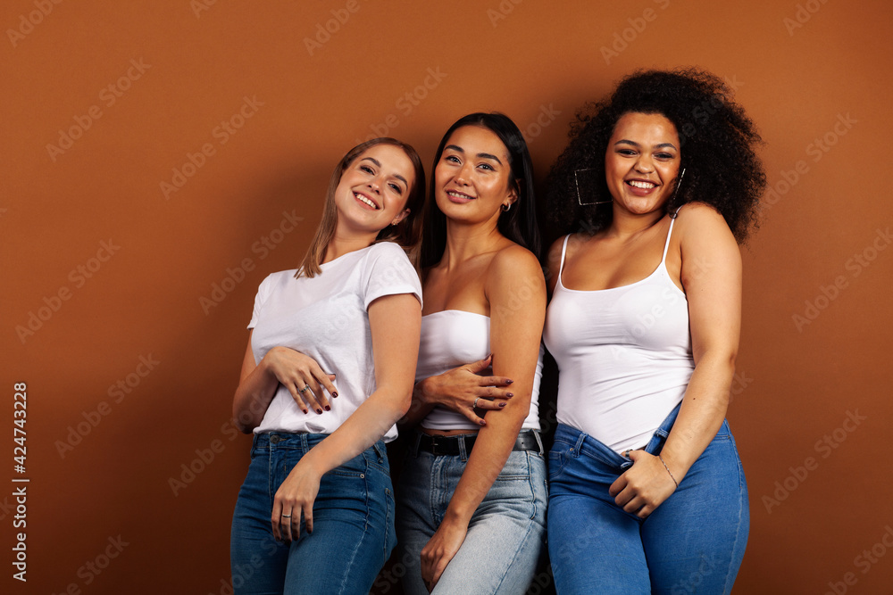 young pretty asian, caucasian, afro woman posing cheerful together on brown background, lifestyle diverse nationality people concept young pretty asian, caucasian, afro woman posing cheerful together on brown background, lifestyle diverse nationality people concept