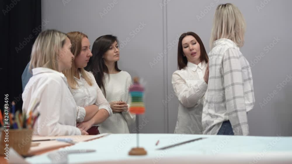 School of young fashion designers: a group of young girls as seamstresses learns to measure on a model. Woman and business, women and fashion industry, female designer in the studio. School of young fashion designers: a group of young girls as seamstresses learns to measure on a model. Woman and business, women and fashion industry, female designer in the studio.