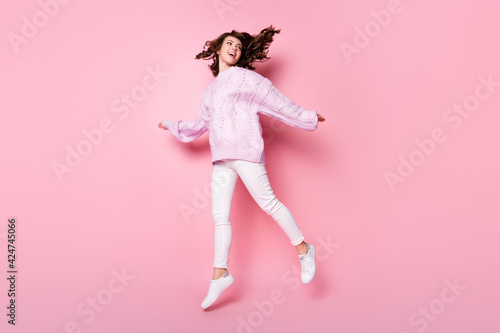 Full length body size view of attractive cheerful wavy-haired girl jumping having fun going isolated on pink pastel color background