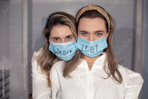 LGBT Lesbian couple in medical protective masks with sign on faces love women moments happiness concept, photo