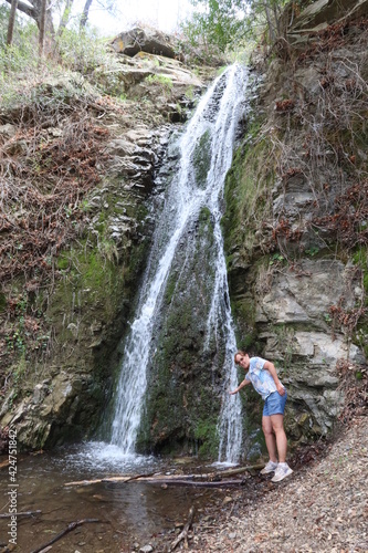 Waterfall on Black Rock with a Woman Standing Next To It putting her hand into the Water