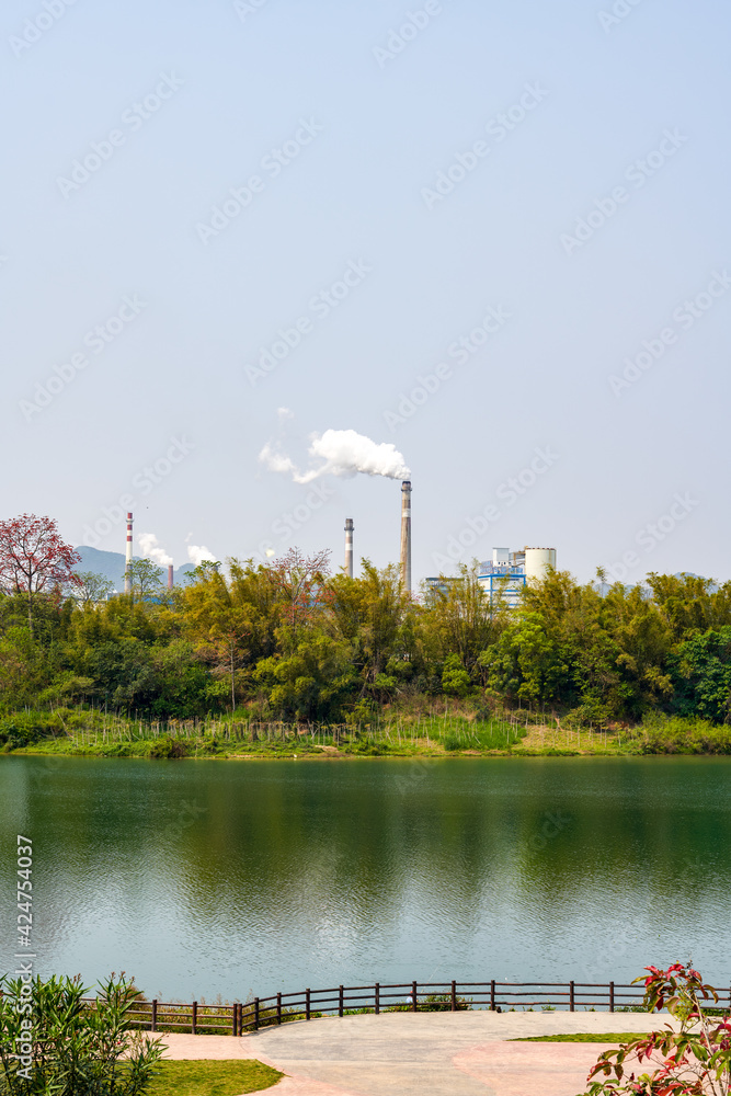 Greening on the banks of the river and industrial factory chimneys in the distance