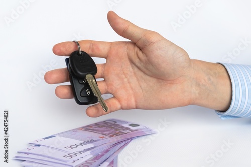 car keys in a man's hand and money, on a white background