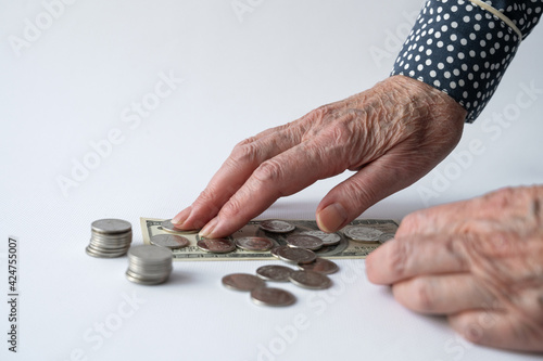 Close-up of an elderly woman's hand counting money on a white background. Retirement savings, home finance