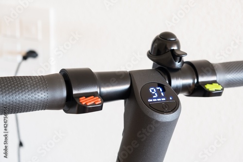 Handlebar of the electric scooter with a display. Indication of the battery charging process, close up 