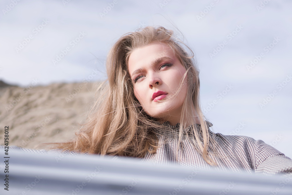 Beauty portrait of a young blond girl in a vintage dress. She is posing on a sandy landscape with harsh sun. Beauty portrait of a young blond girl in a vintage dress. She is posing on a sandy landscape with harsh sun.