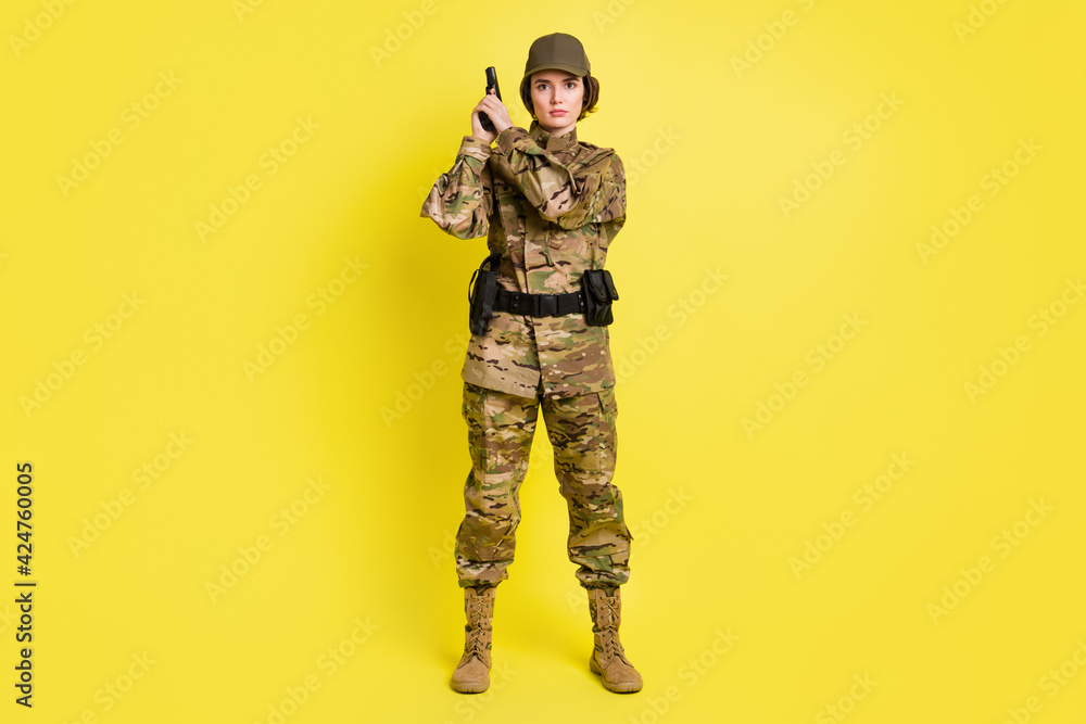 Full size portrait of concentrated military girl standing hands hold pistol isolated on yellow color background