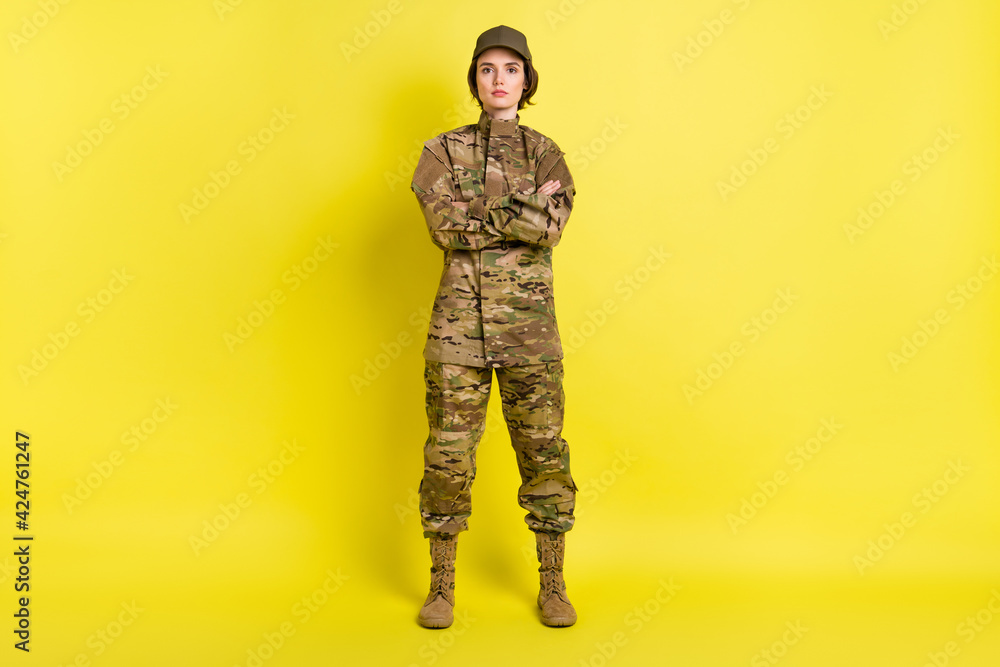 Full size portrait of military girl standing crossed arms look camera isolated on vivid yellow color background Full size portrait of military girl standing crossed arms look camera isolated on vivid yellow color background